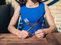 Young woman sitting at table with fork and knife Royalty Free Stock Photo