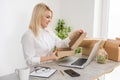 Young woman sitting at table, opening postal packet, smiling, box Royalty Free Stock Photo