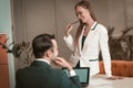 Young woman sitting on the table and sexually looking at young man. Two young and attractive colleagues man and woman Royalty Free Stock Photo