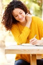 Young woman sitting at table writing in book Royalty Free Stock Photo