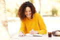 Young woman sitting at table writing in diary Royalty Free Stock Photo