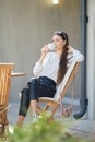 Young woman sitting on the terrace of the cafe in sunny day and drinking coffee Royalty Free Stock Photo