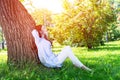 Young woman sitting under tree in summer park Royalty Free Stock Photo