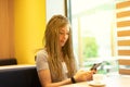 Young woman sitting using a mobile in a cafeteria Royalty Free Stock Photo