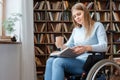 Young woman sitting in a wheelchair disability concept reading book Royalty Free Stock Photo