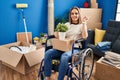 Young woman sitting on wheelchair moving to a new home smiling looking to the camera showing fingers doing victory sign Royalty Free Stock Photo