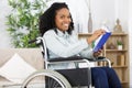 Young woman sitting in wheelchair reading book Royalty Free Stock Photo