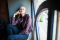 Young woman is sitting on a window sill in a cafe and enjoy free time Royalty Free Stock Photo