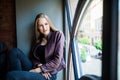 Young woman is sitting on a window sill in a cafe and enjoy free time Royalty Free Stock Photo