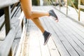 Young woman sitting on a wooden bridge railing in jeans sneakers Royalty Free Stock Photo