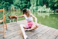 Young woman sitting on a wooden pier on a lake and playing with her dog Royalty Free Stock Photo