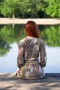 Young woman sitting on wooden pier looking at lake Royalty Free Stock Photo