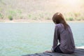 young woman sitting on wooden raft front of herself are blue water background. this image for travel,nature and portrait Royalty Free Stock Photo