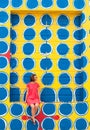 A young woman sitting on a yellow wall with a pattern of blue-white dots Royalty Free Stock Photo