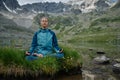 Young woman is sitting in yoga lotus position against the turquoise lake in the mountains Royalty Free Stock Photo