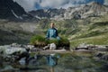 Young woman is sitting in yoga lotus position against the turquoise lake in the mountains Royalty Free Stock Photo