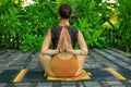 Young woman sitting on yoga mat, meditating, practicing yoga and pranayama. Lotus pose with hands in namaste mudra. View from back Royalty Free Stock Photo