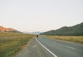 Young woman on skateboard on the road against beautiful mountain landscape, Chuysky tract, Altai