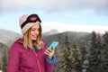 Young woman with ski goggles using smartphone