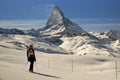 Young woman on ski in ski helmet and mask standing on untouched snow near Matterhorn mountain, freeride skiing in Alps