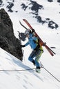 Young woman ski mountaineer climbing on rope on rock