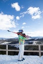 young woman in ski suit holds skis on shoulder, stands on top of a snow-covered mountain slope Royalty Free Stock Photo