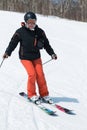 Young woman skier coming down the ski from a mountain on a sunny