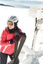 Young woman skier at winter ski resort in mountains, holding skies Royalty Free Stock Photo