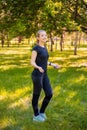 A young woman with a skipping rope in her hands stands on the lawn in a summer park. Royalty Free Stock Photo