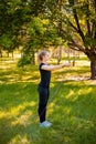 A young woman with a skipping rope in her hands stands on the lawn in a summer park. Royalty Free Stock Photo