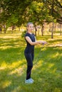A young woman with a skipping rope in her hands stands on the lawn in a summer park. Royalty Free Stock Photo
