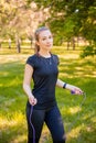 A young woman with a skipping rope in her hands stands on the lawn in a summer park. Royalty Free Stock Photo