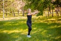 A young woman with a skipping rope in her hands stands on the lawn in a summer park. Royalty Free Stock Photo