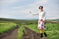 Young woman in skirt hitchhiking near a countryside road Royalty Free Stock Photo