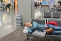 Young woman sleeping at the airport while waiting for her flight. Tired female traveler sleeping on the airpot departure gates