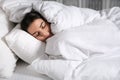 Young woman sleeping in bed covered with white blanket Royalty Free Stock Photo