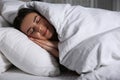 Young woman sleeping in bed covered with white blanket Royalty Free Stock Photo
