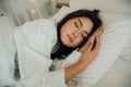 Young woman sleeping in bed, her head resting on a white pillow with her hands beside her head. Royalty Free Stock Photo