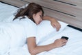 Young Woman Sleeping Cozily and Holding Phone