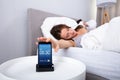 Woman sleeping near alarm set on mobile phone
