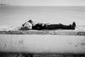 Young Woman Sleeping on Sea Wall in Cadiz, Spain.