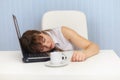 Young woman sleeps on laptop keyboard on workplace