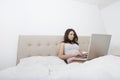 Young woman in sleepwear using laptop in bed Royalty Free Stock Photo