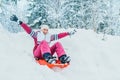 Young woman slide down from snow slope sitting in one slide.Winter activities concept image