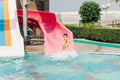 Young woman slide in pool after going down water slide at sunny day in water Aqua park. Refreshing at heat weather Royalty Free Stock Photo