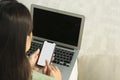 Young woman with smartphone and laptop indoors, closeup Royalty Free Stock Photo