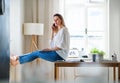 Young woman with smartphone and laptop indoors in home office, working. Royalty Free Stock Photo