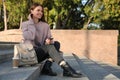 Young woman with smartphone and stylish beige backpack on stairs outdoors, space for text Royalty Free Stock Photo