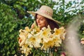 Young woman smelling flowers in garden. Gardener taking care of lilies. Girl growing plants. Gardening concept Royalty Free Stock Photo