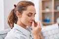 Young woman smelling marihuana bud sitting on sofa at home